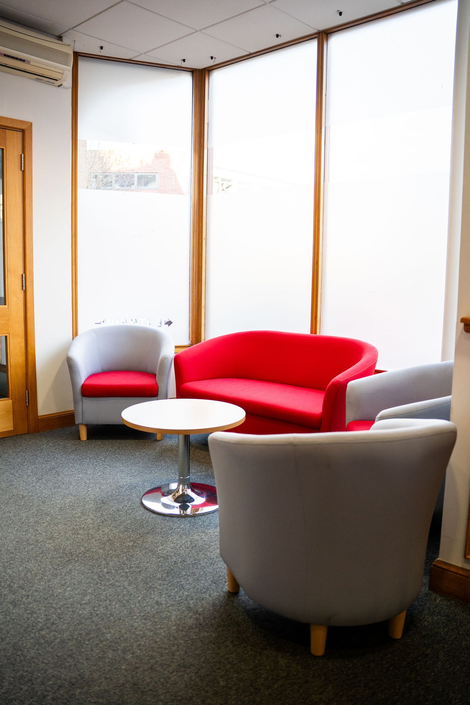 Modern office waiting area with curved seating and large windows providing natural light.