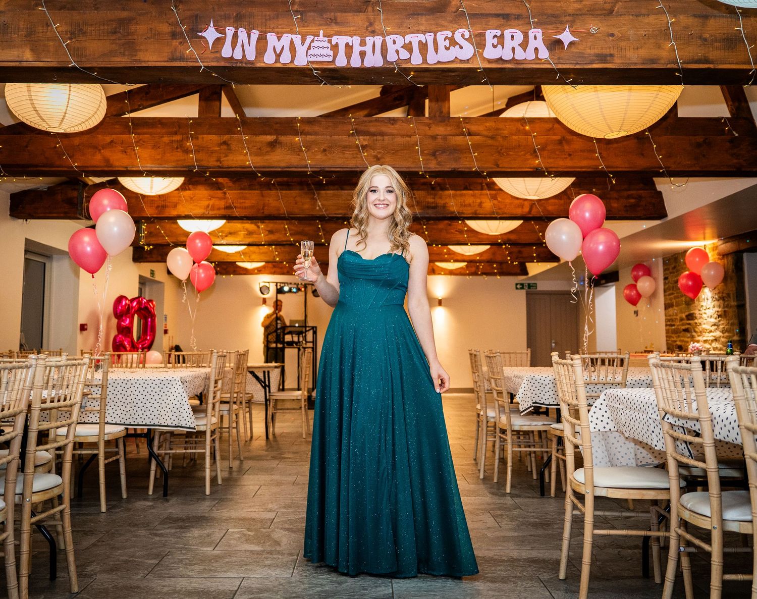 Decorated event venue with wooden beams, paper lanterns, and pink balloons for a celebration.