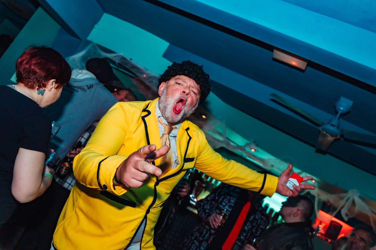 Person in bright yellow clothing dancing at a nightclub party.