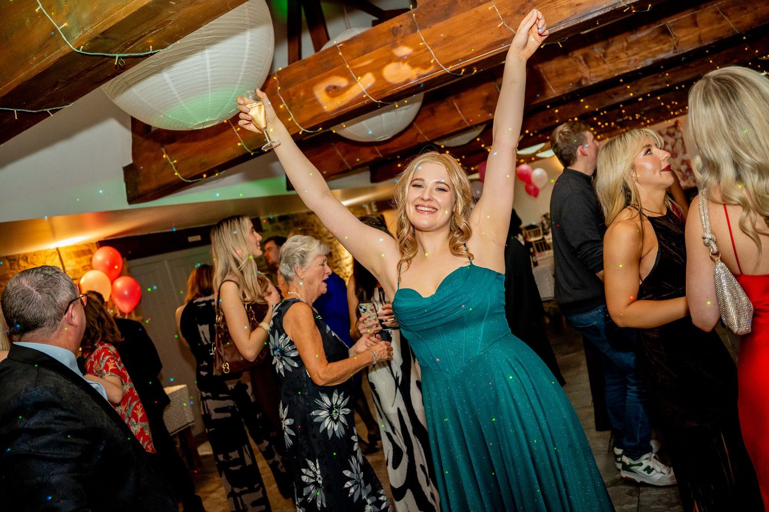 Celebratory dance moves captured at a festive indoor event with wooden ceiling features.