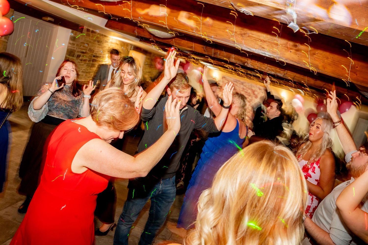 People dancing and celebrating at a lively indoor party with atmospheric lighting.