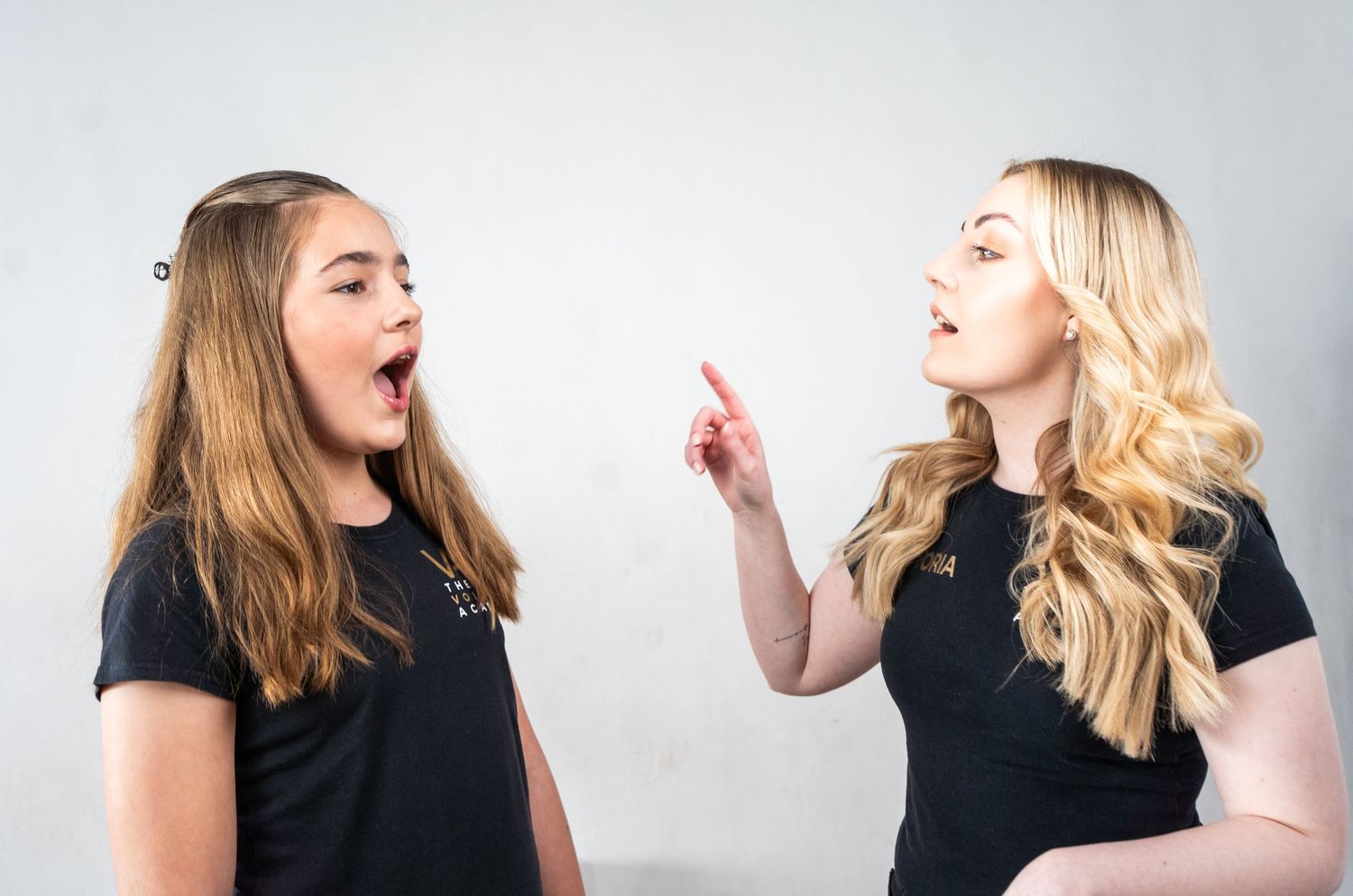Two performers practicing vocal techniques together in a bright studio setting.