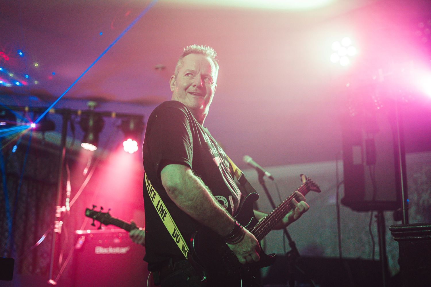 Guitarist performs on stage with colorful lighting effects creating an atmospheric concert ambiance.