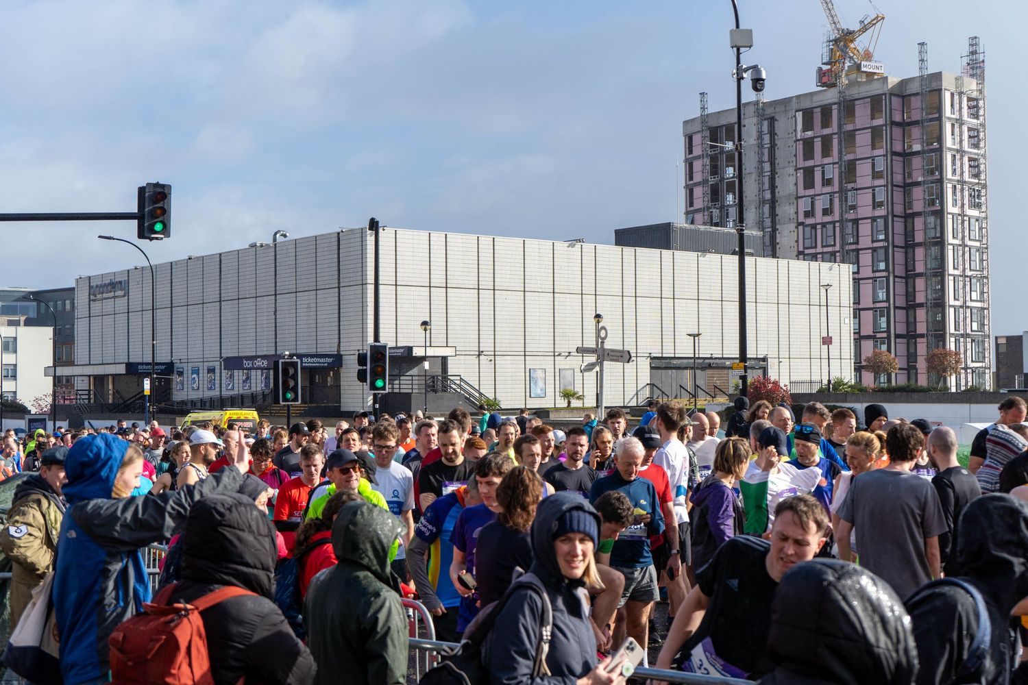 Large crowd of runners gathered outside modern building before race start.