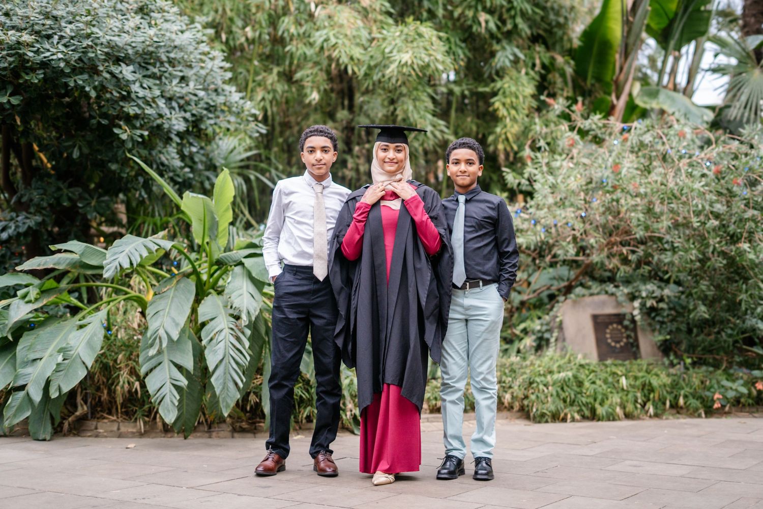 Candid family moment captured in garden setting during graduation celebration.