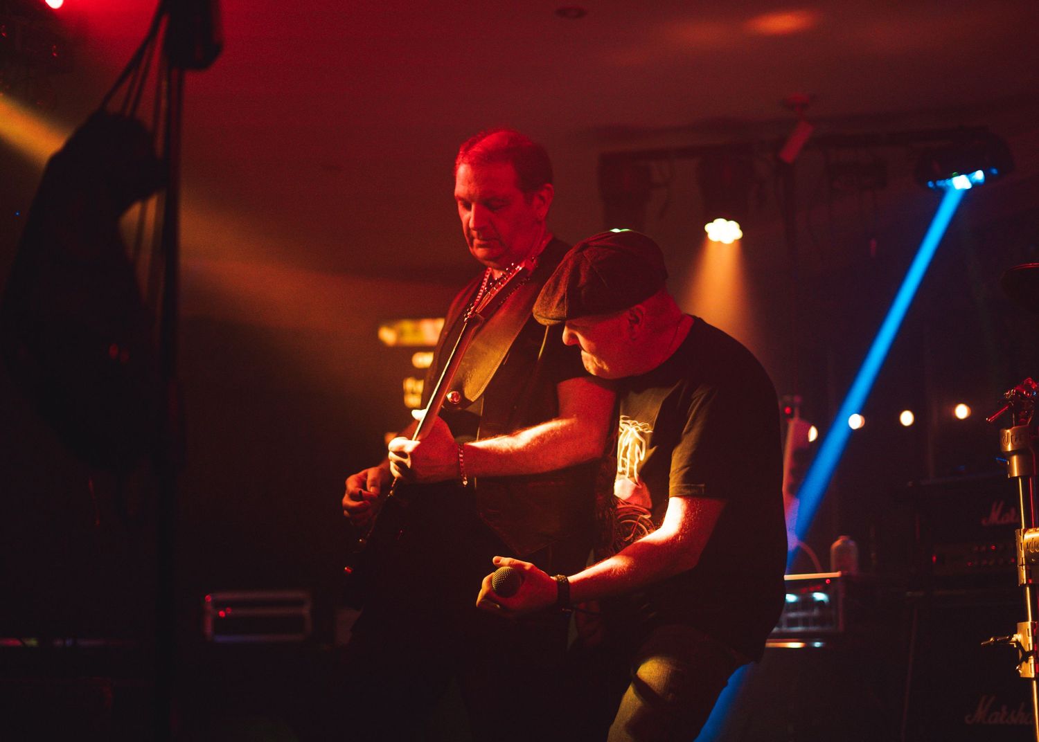 Musicians performing on stage with dramatic red and blue lighting effects.