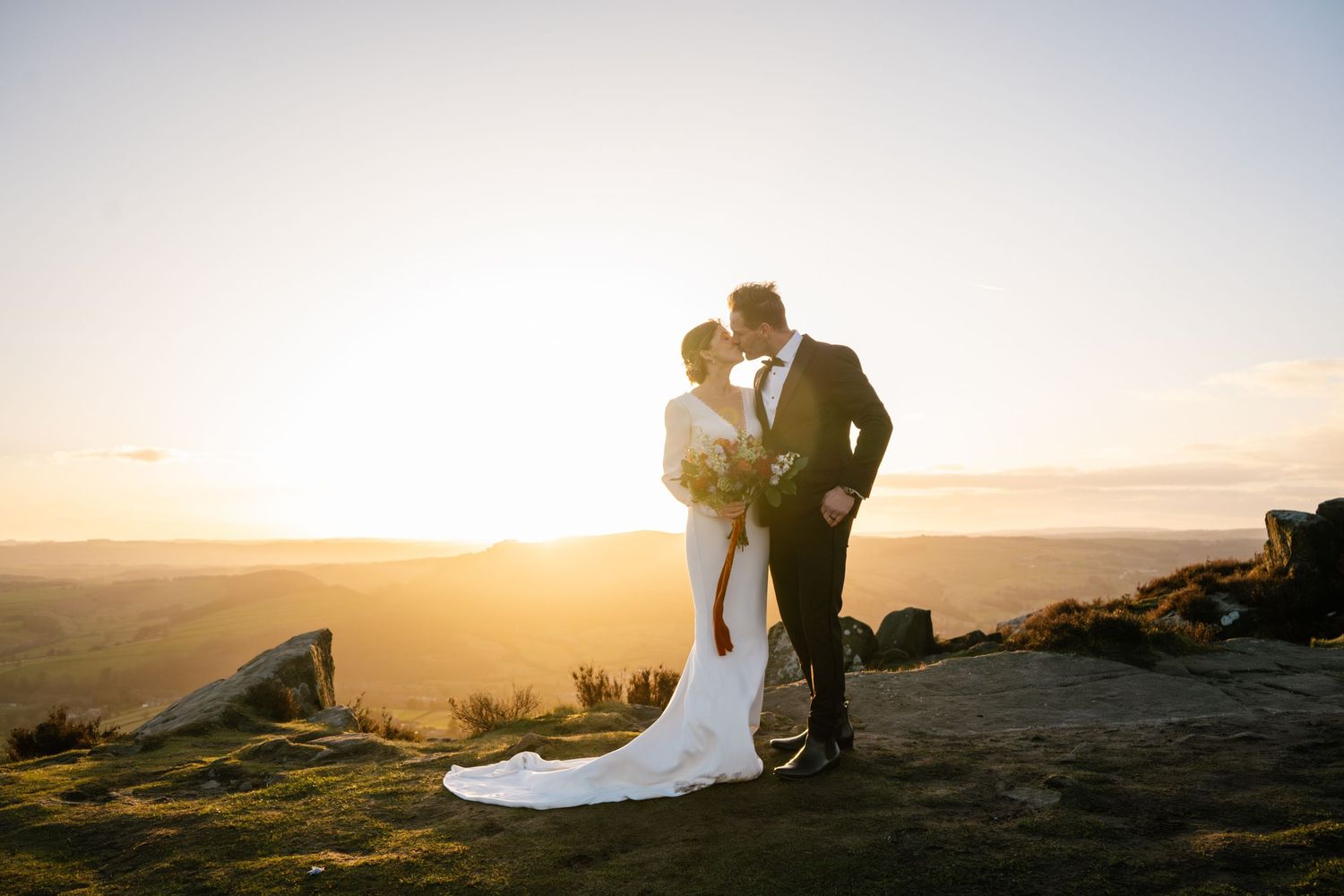 Romantic sunset wedding portraits captured against a dramatic mountain landscape.