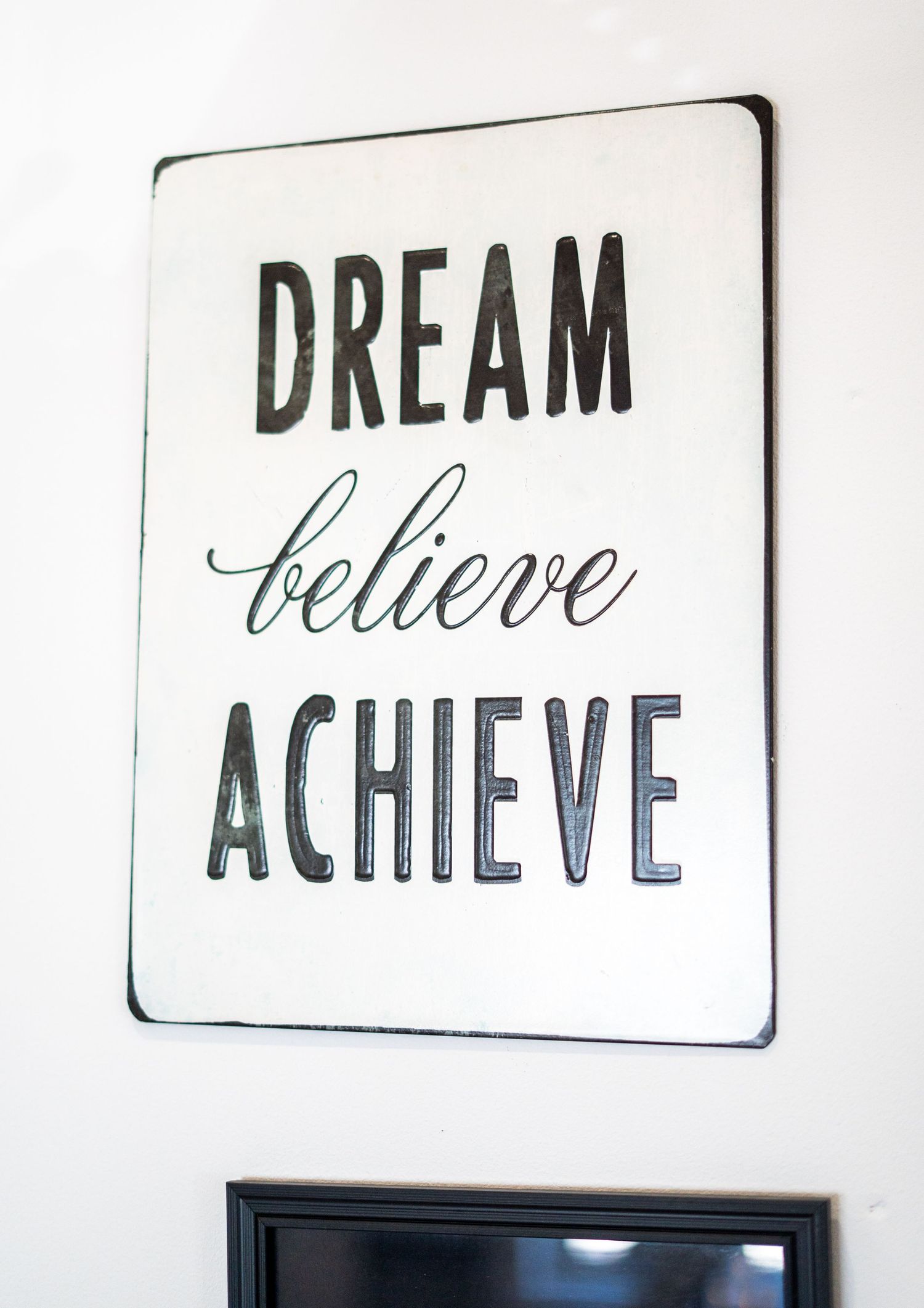 Motivational wall art displaying 'DREAM ACHIEVE' text in elegant typography.