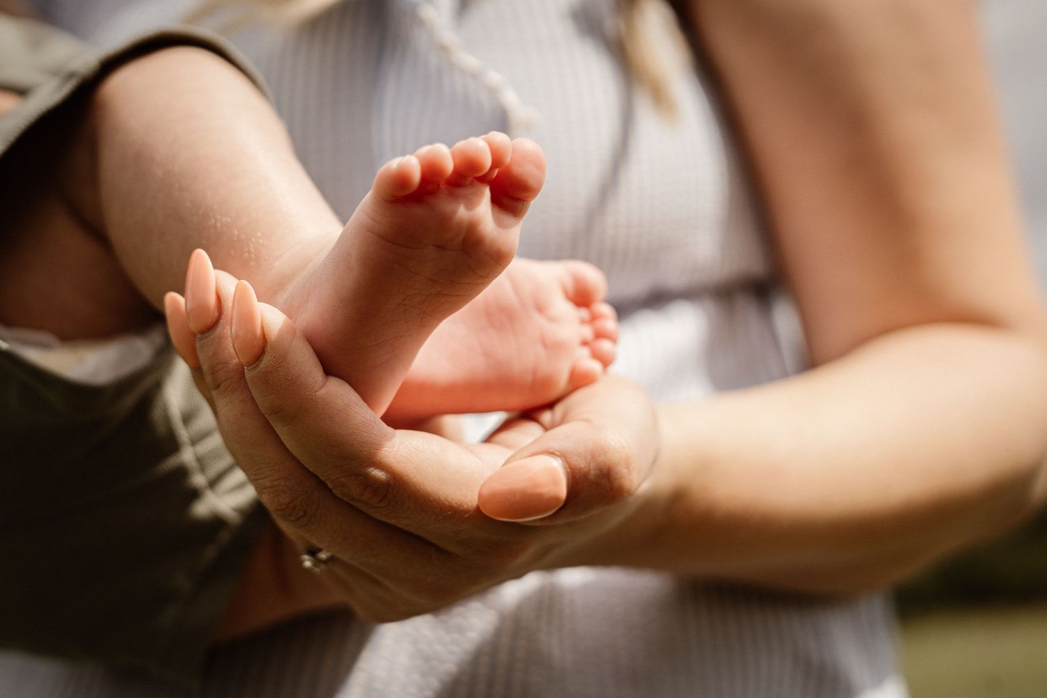 Close-up detail of tiny baby feet being held with care and love.