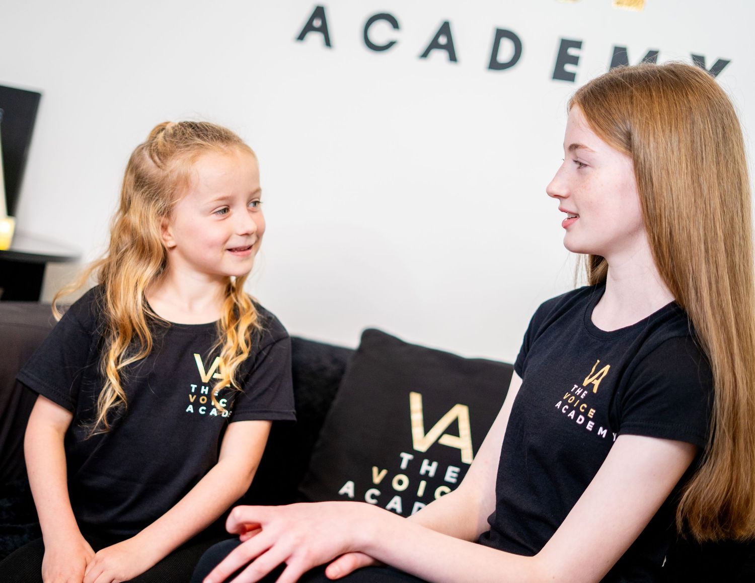 Students in Voice Academy branded attire interacting during performance workshop.