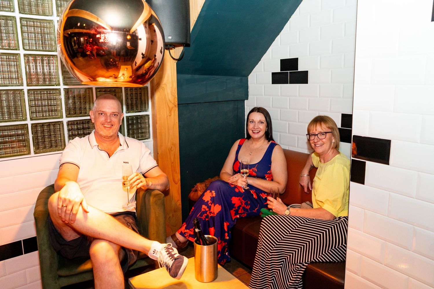 Friends relaxing in a casual lounge setting with white walls.