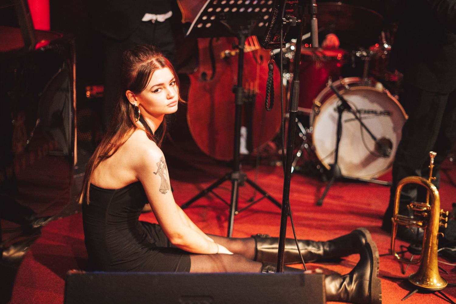 Musicians performing on stage with red theatrical lighting and professional sound equipment.
