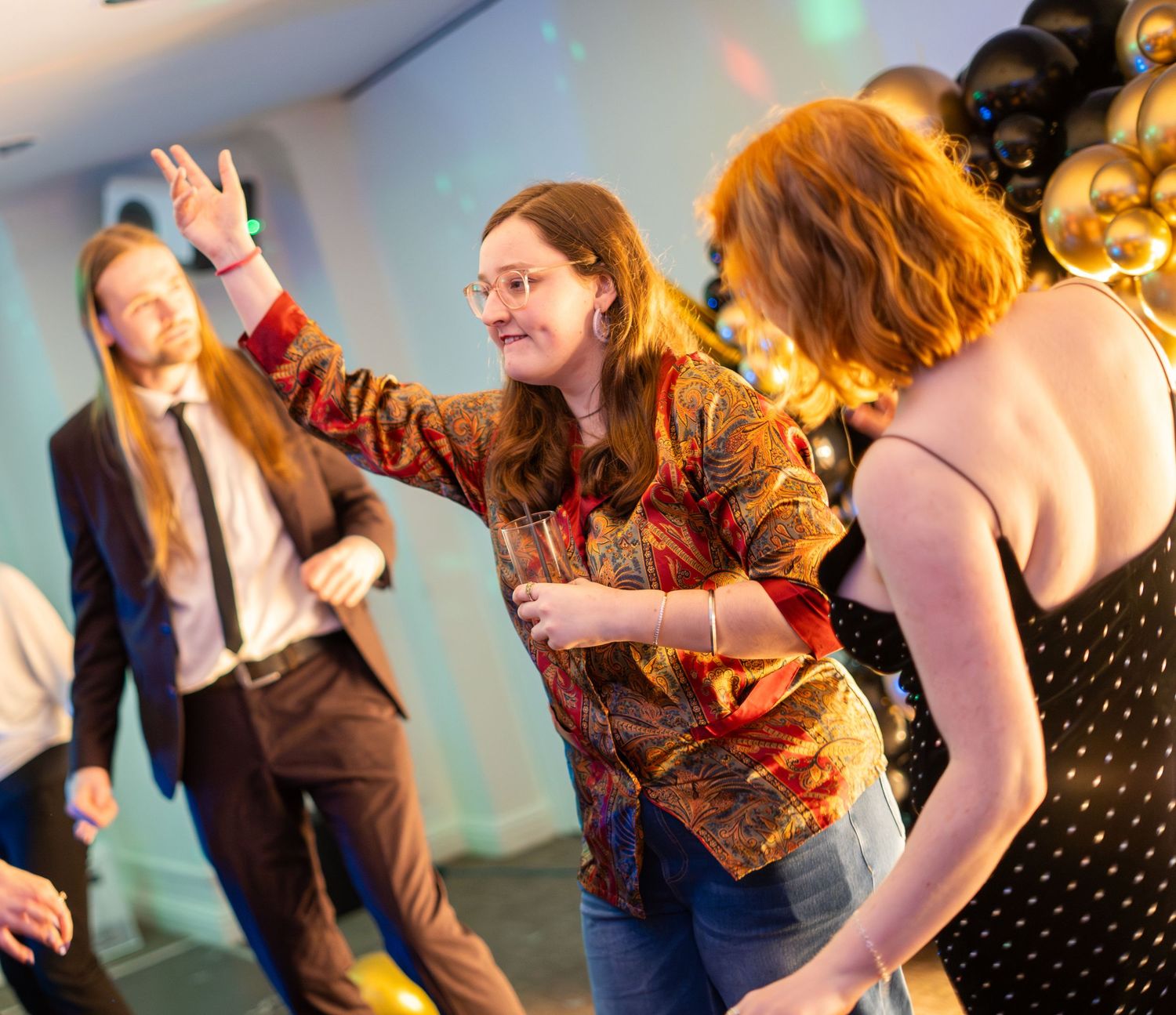 Party guests dancing and socializing under atmospheric venue lighting.