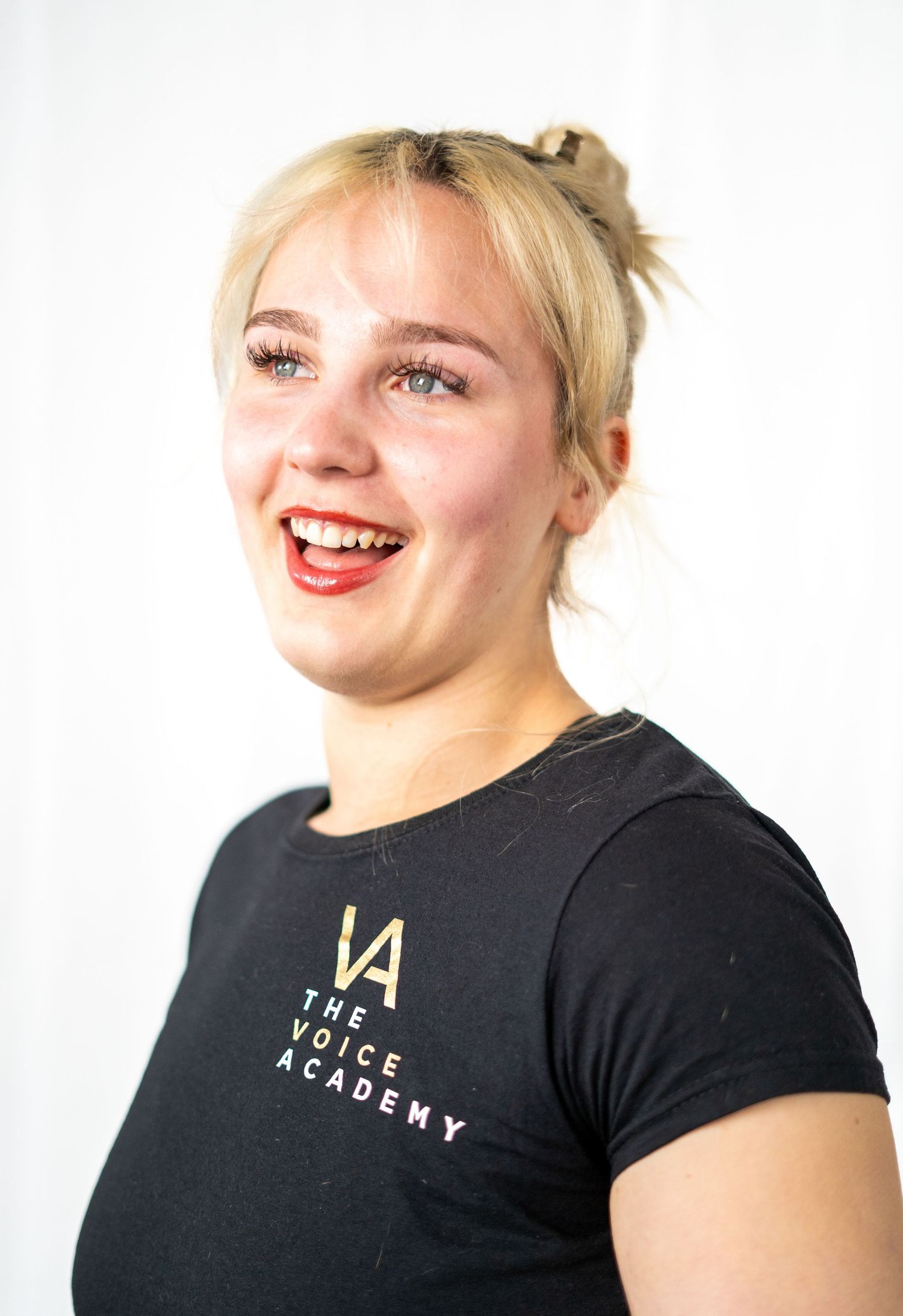 People wearing Voice Academy branded shirts smiling during performance practice.