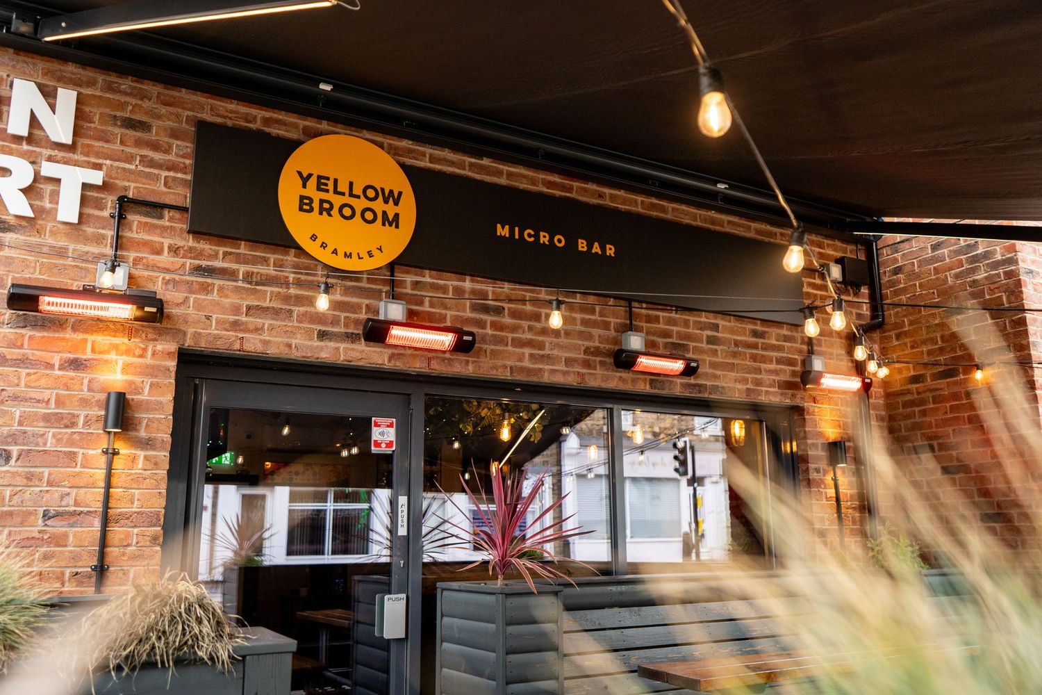 Exposed brick wall with string lights and rustic decor creating a warm ambiance in a restaurant setting.