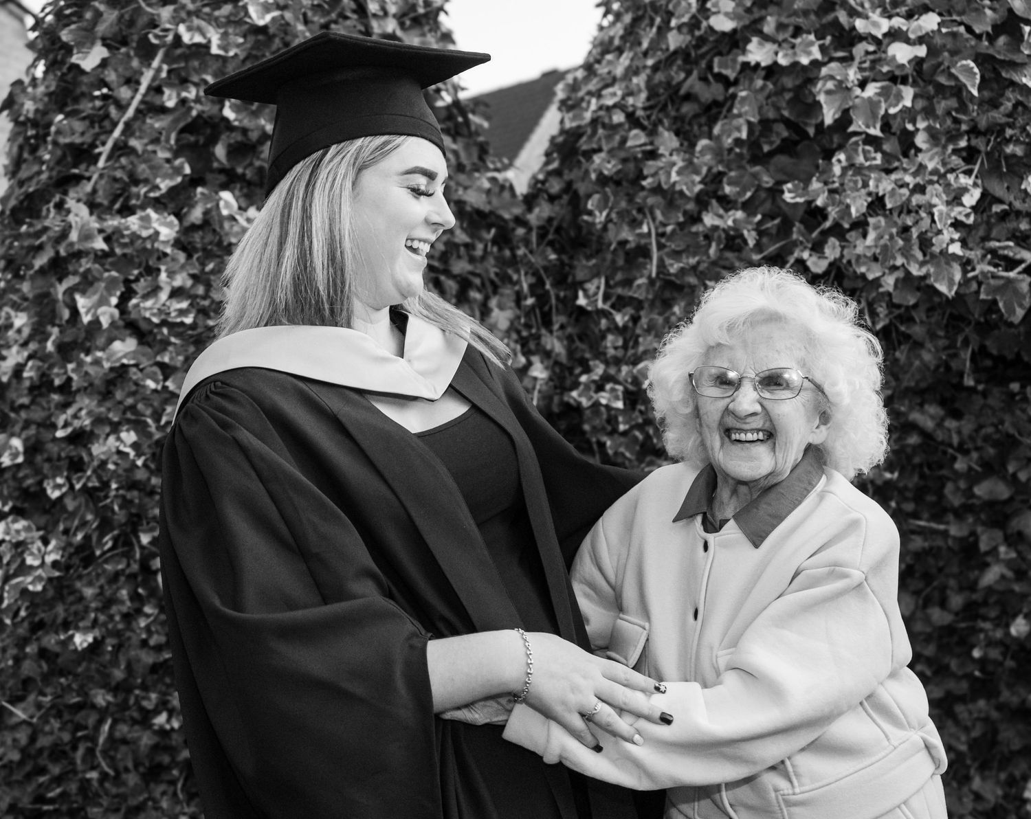 Black and white graduation photos showing emotional celebration between graduate and loved one.