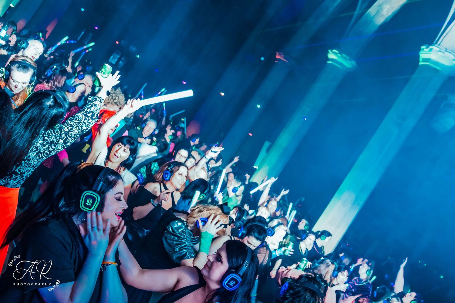 Concert audience silhouetted against bright blue stage lighting during a live performance.