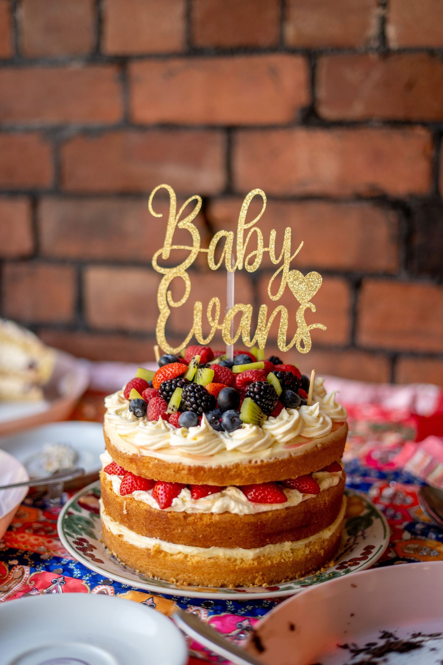 Beautiful layered cream cake decorated with fresh berries and gold cake topper.