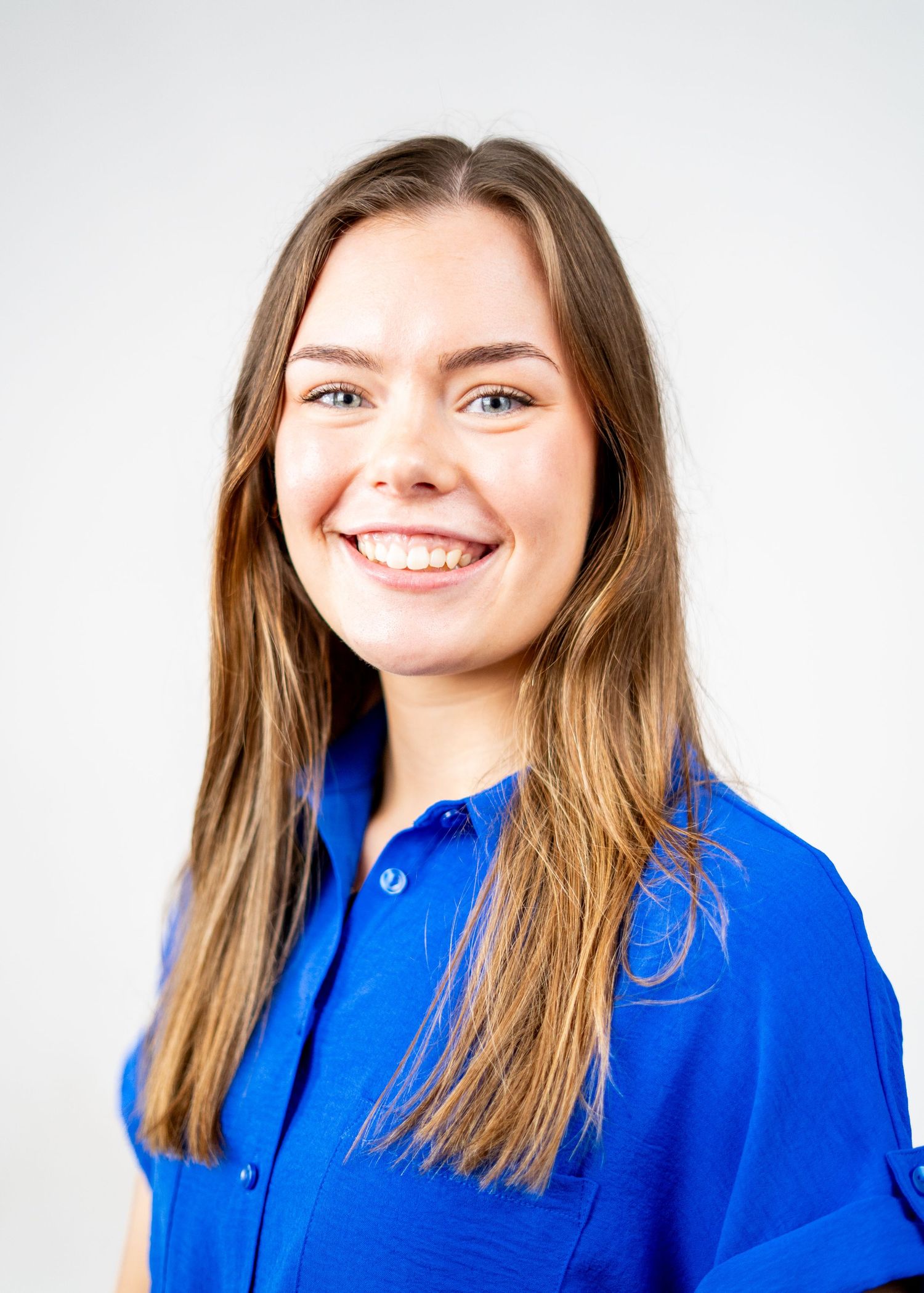 Professional portrait of a person wearing a bright blue button-up shirt against a light backdrop.