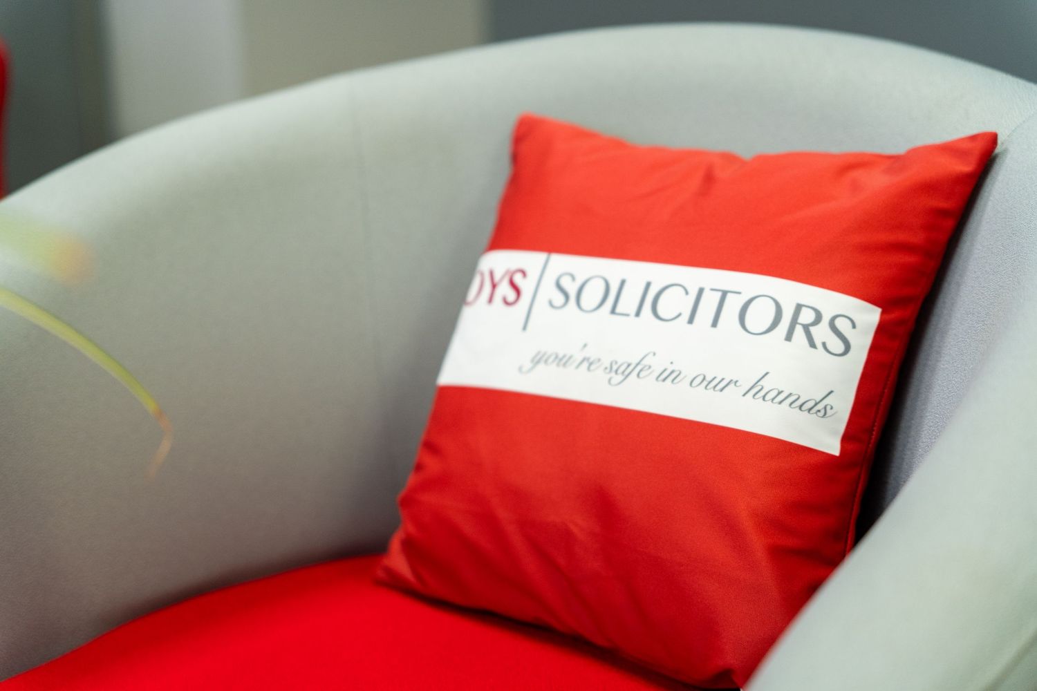 Red decorative throw pillows with Foys Solicitors branding on light colored furniture.