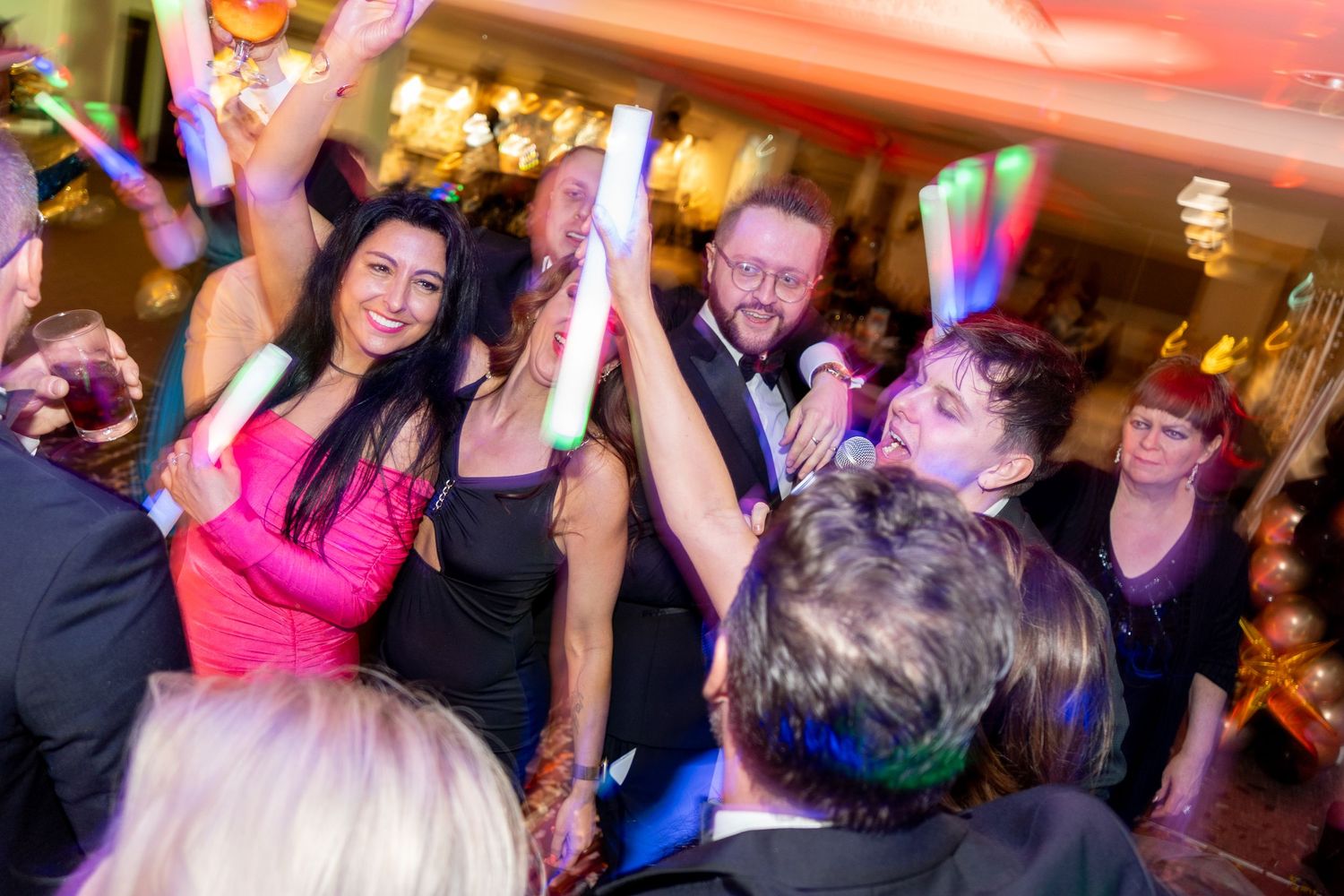 Crowded dance floor with vibrant red and blue lighting at an indoor event.