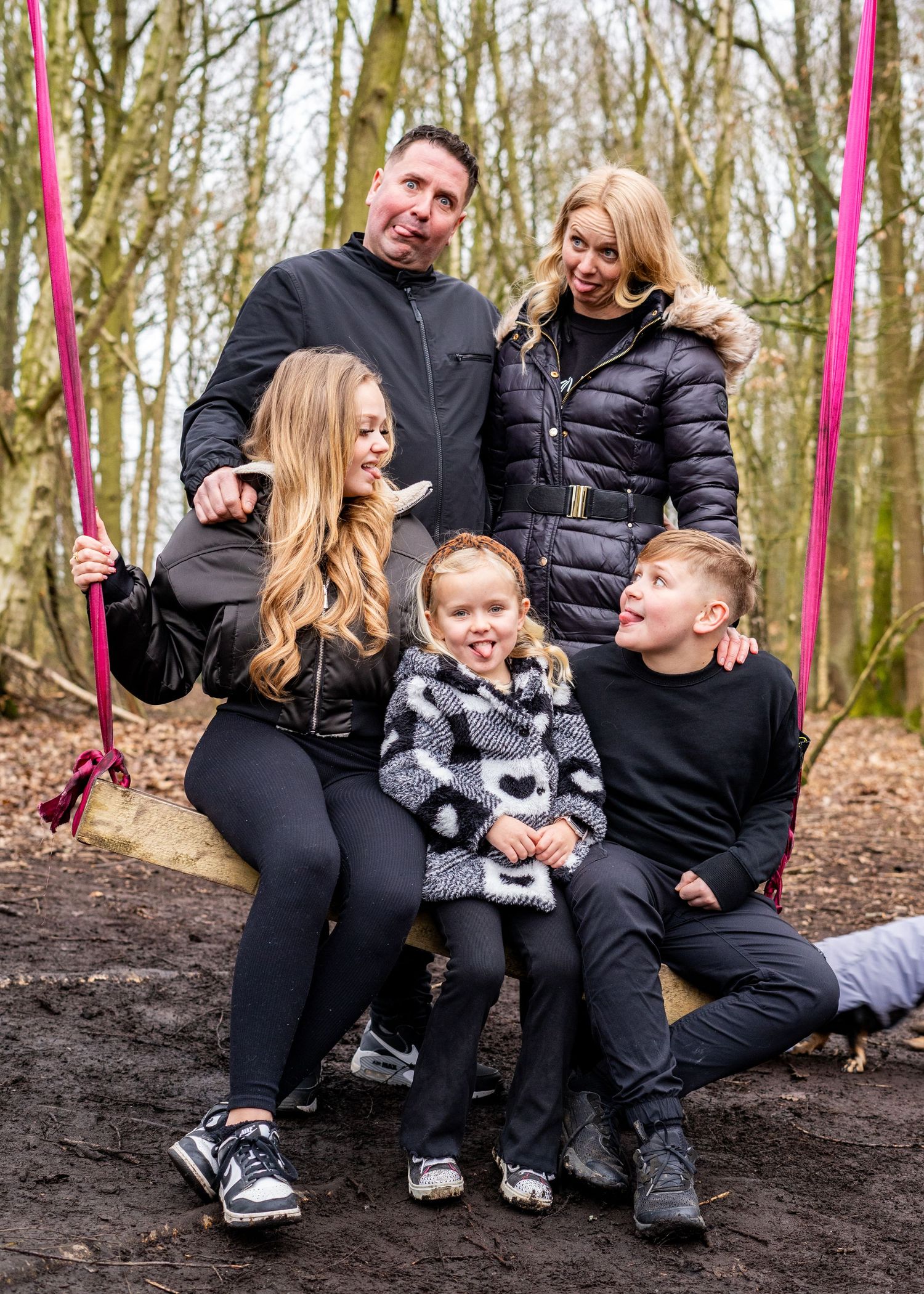 Family enjoying a relaxed moment together on forest ground during winter.