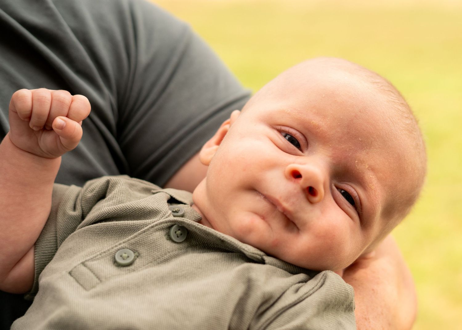 Peaceful newborn baby resting in olive green clothing.