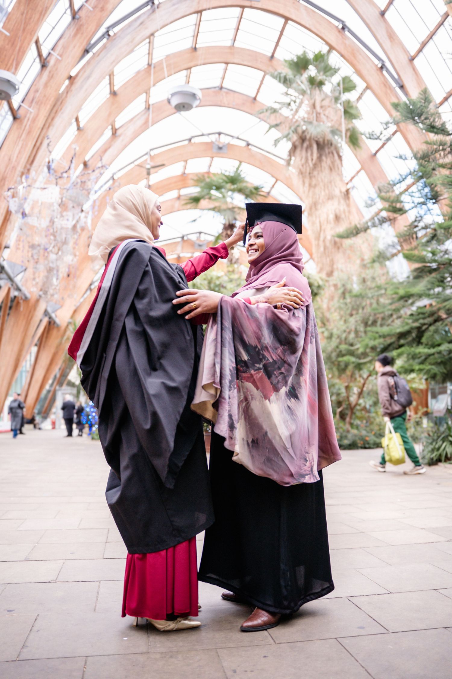Graduates pose under an arched walkway in traditional academic attire.