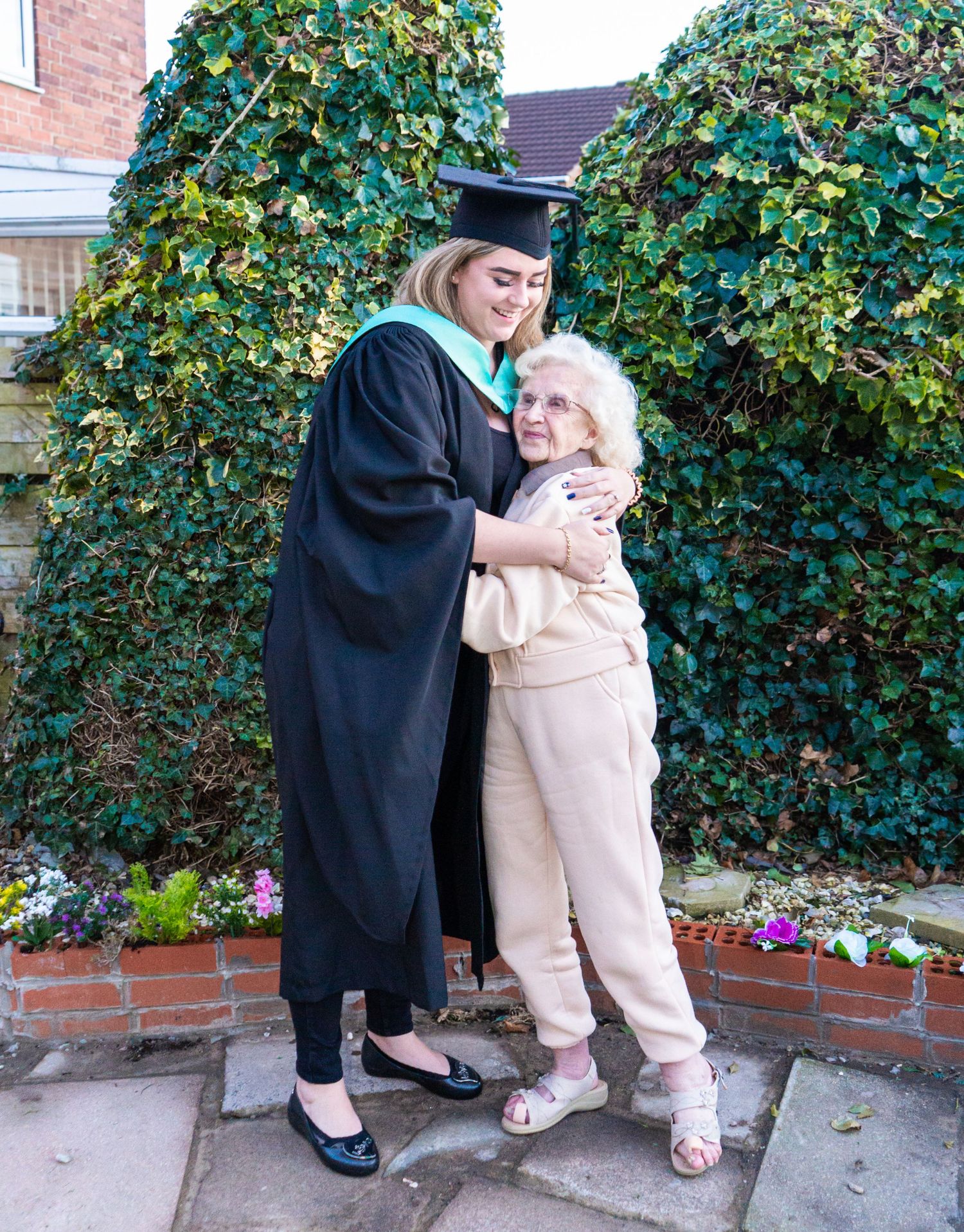 Candid graduation photos capturing tender moments between graduate and elderly relative in garden setting.