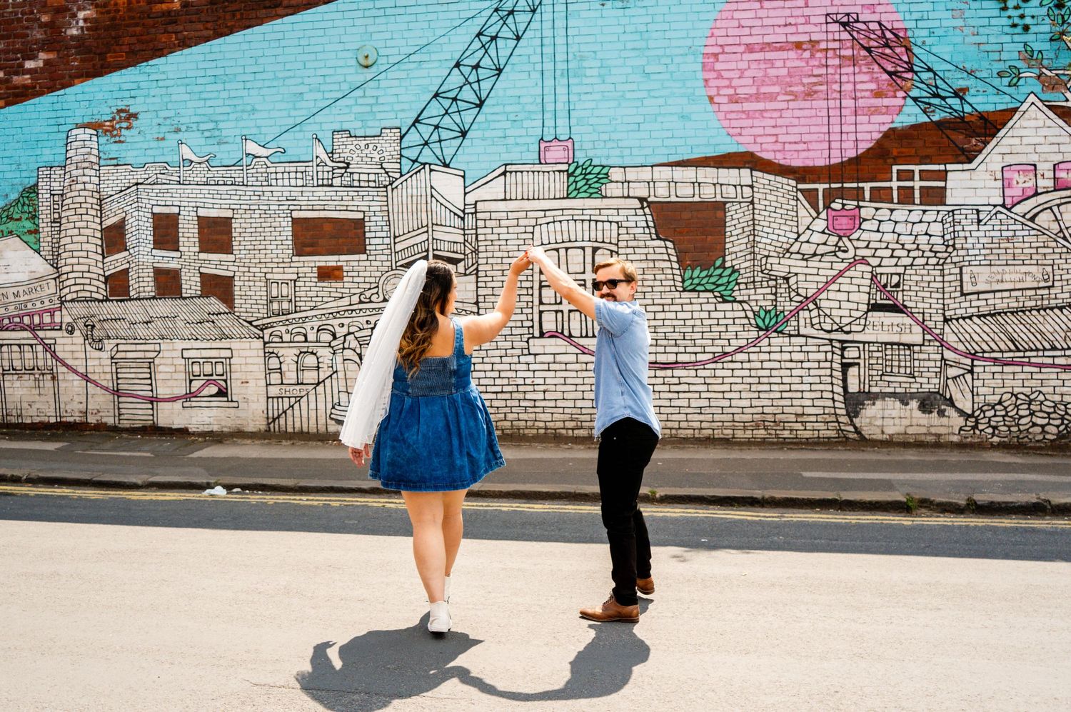 A couple posing against a colorful mural wall with urban art.