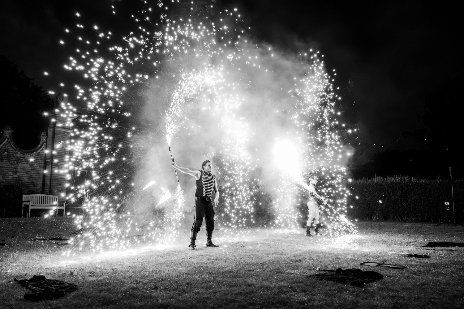 Dramatic black and white firework display creating sparks and light trails against dark night sky.