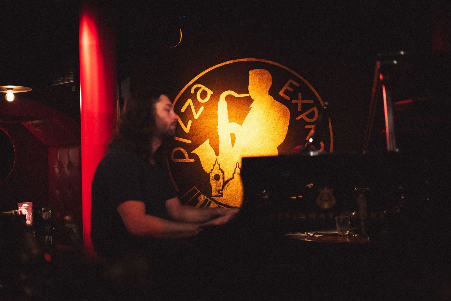 A moody nightclub interior with warm glowing lights and silhouettes in the background.
