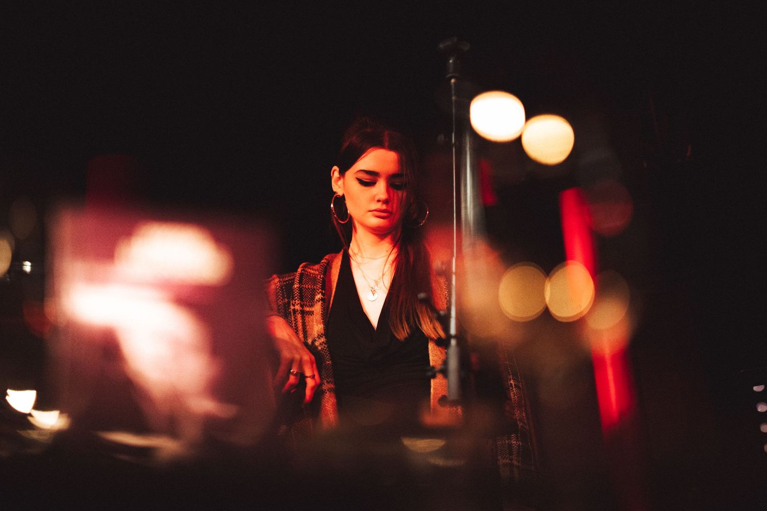 A performer in dramatic lighting on stage with soft bokeh effects in the background.