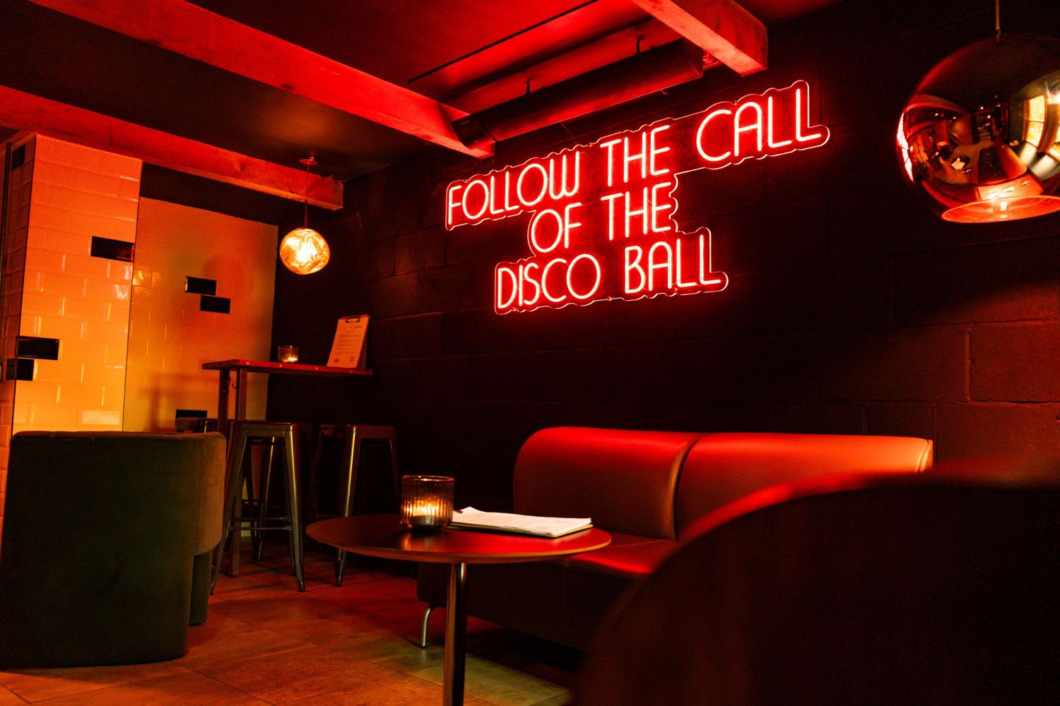 Modern bar interior with red neon signage and dramatic lighting creating a vibrant nightlife atmosphere.