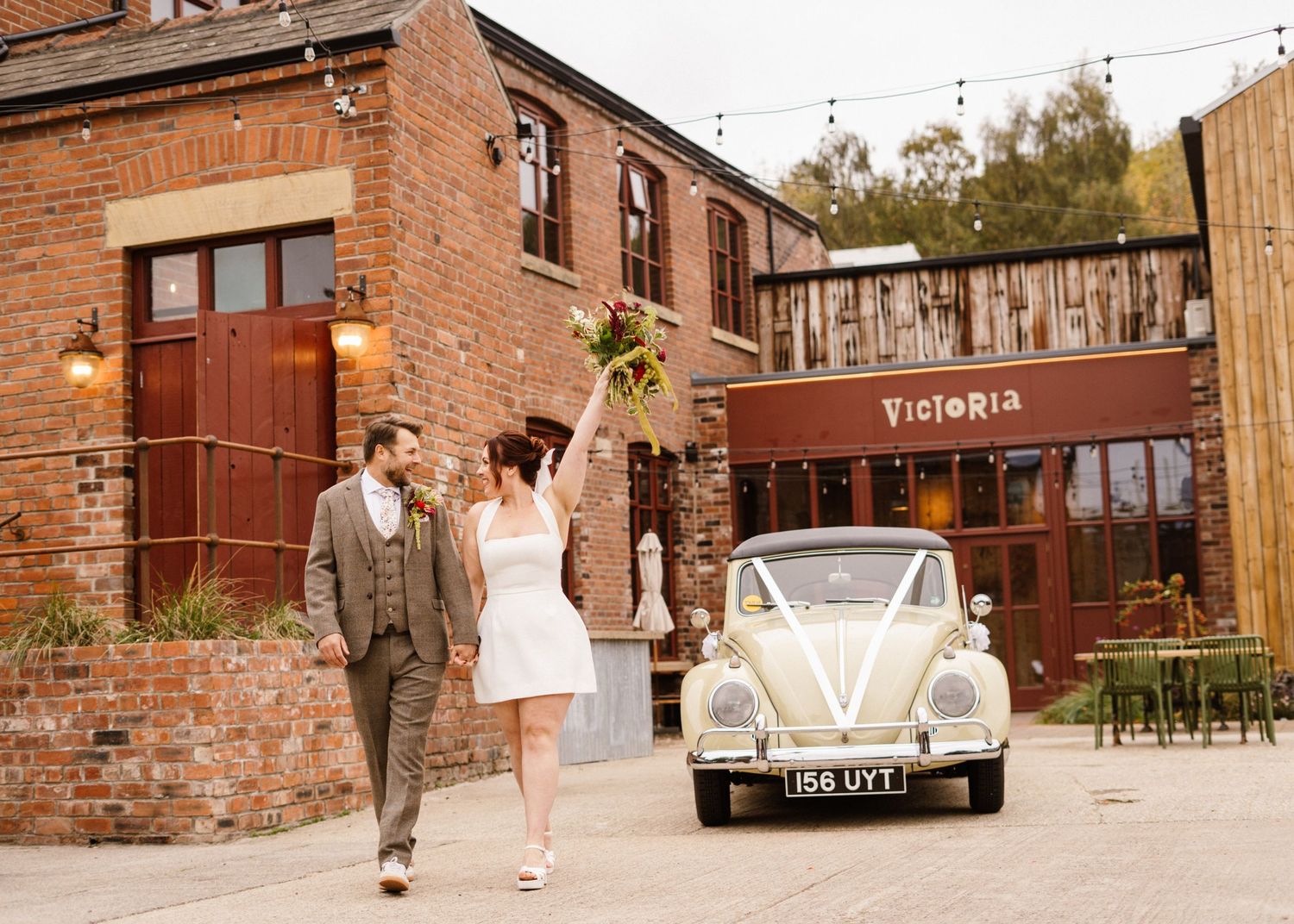 Vintage-themed wedding photos at an industrial brick venue with string lights and classic cars.