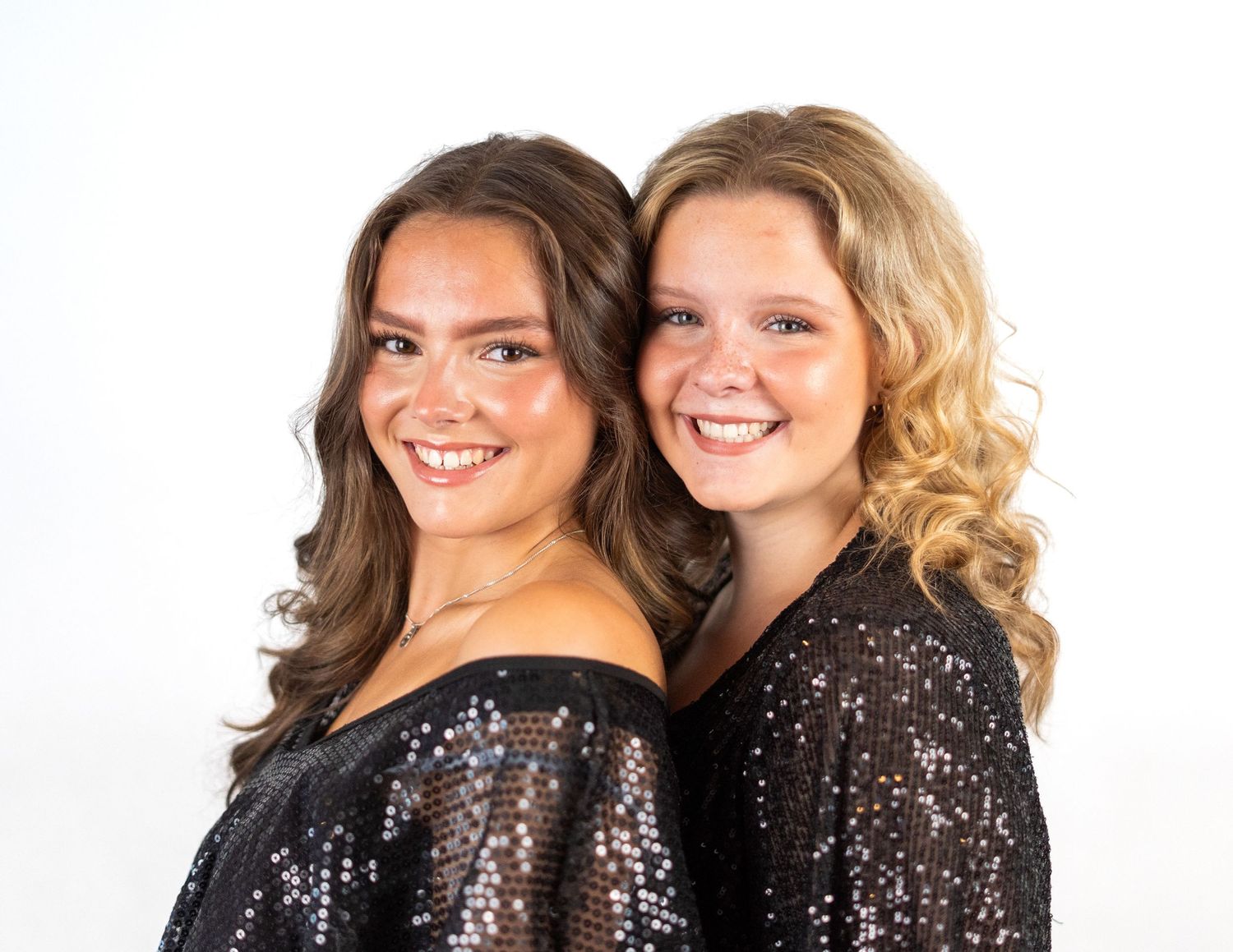 Two singers in matching black outfits pose together for promotional photos.