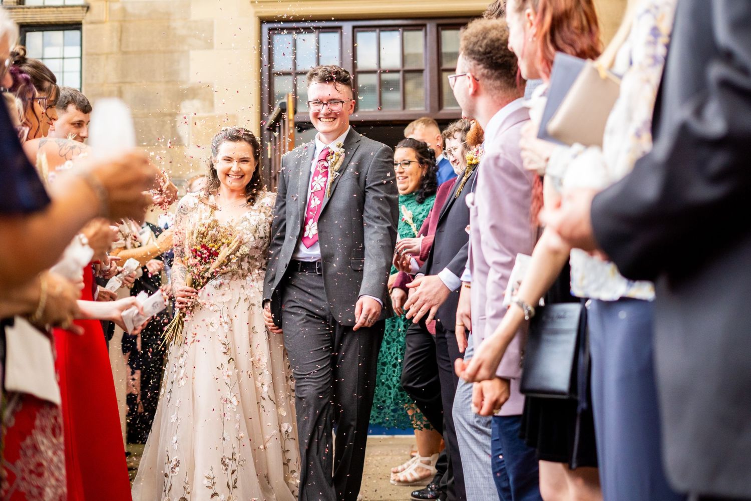 Wedding guests celebrate and throw confetti during a joyous outdoor reception.