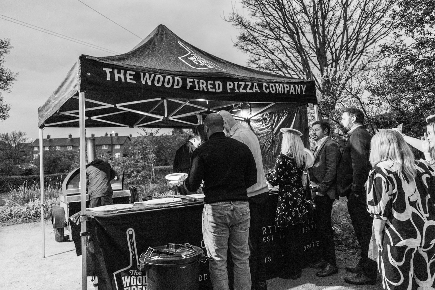 Wood Fired Pizza Company tent with customers lined up at an outdoor event.