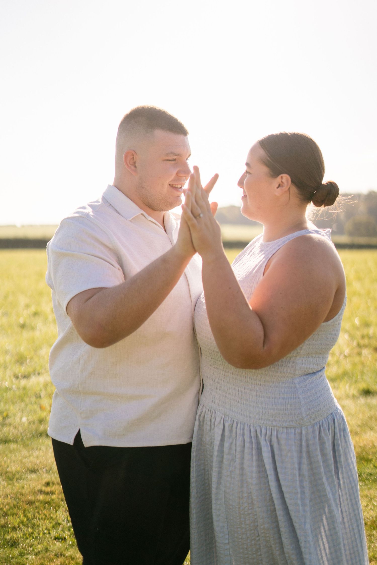 Intimate moment between couple in white and grey clothing during outdoor photoshoot.