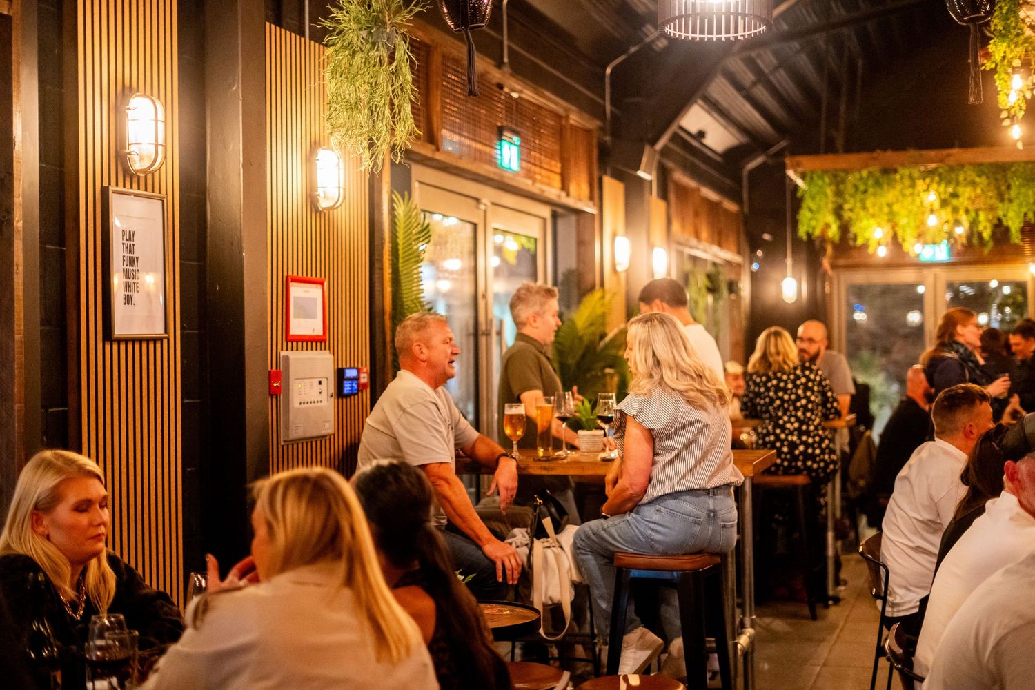Crowded restaurant scene with wood paneling and ambient lighting creating an intimate atmosphere.