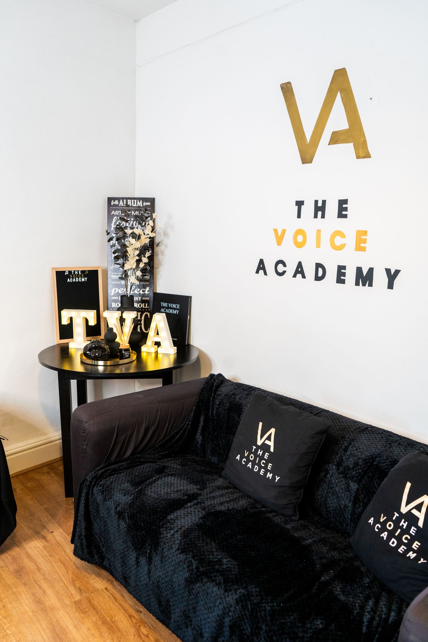 Modern room setup with TVA branding and black couch against white walls.