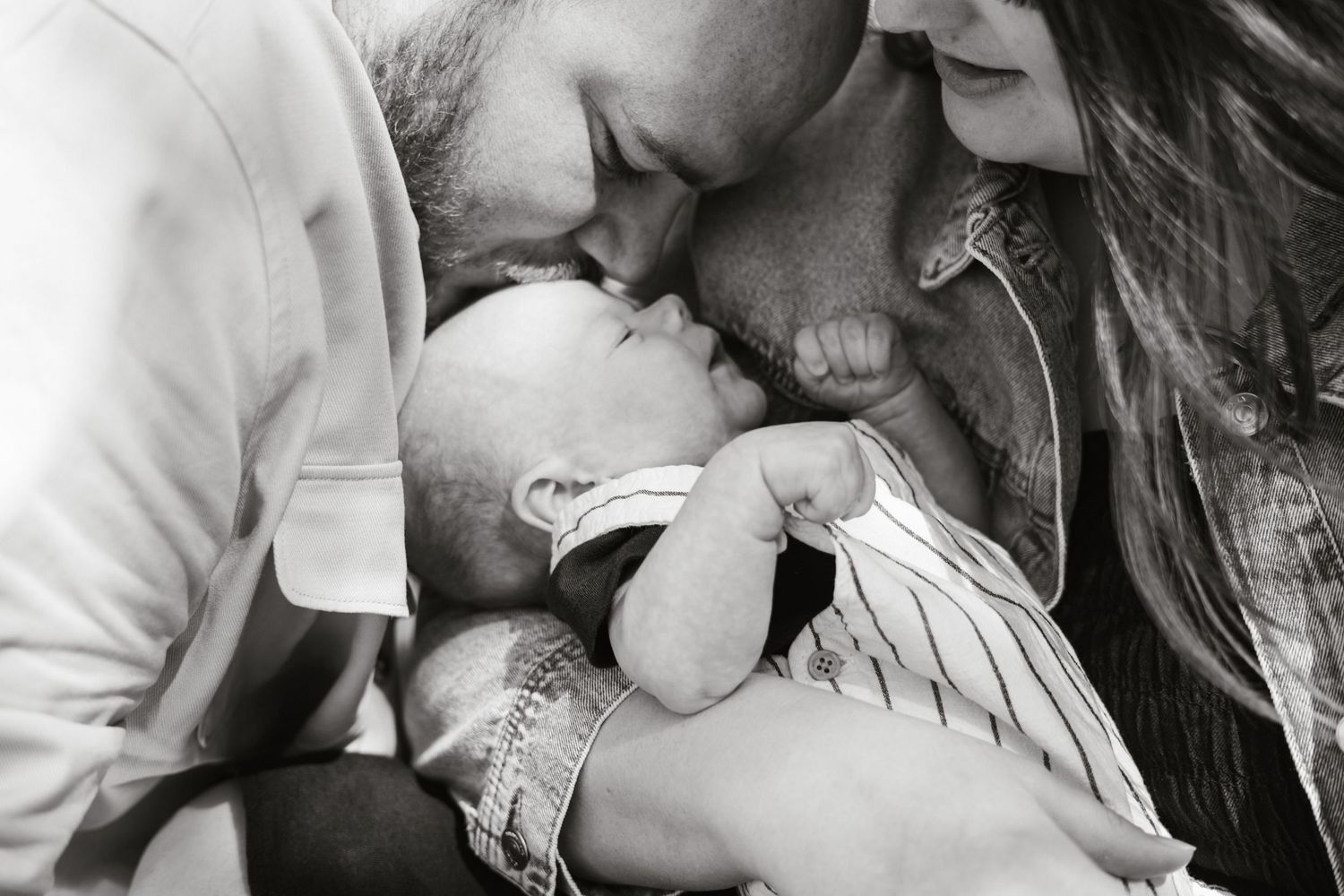 Black and white close-up portrait of family sharing tender moment.