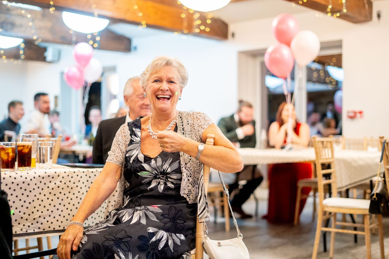 Lively party scene with guests dancing and celebrating in a rustic venue with wooden beams.