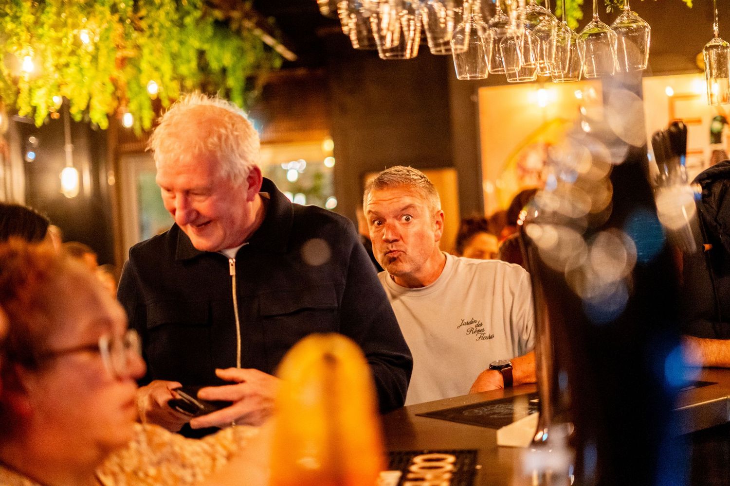 Customers enjoying social gathering at illuminated bar counter during evening hours.