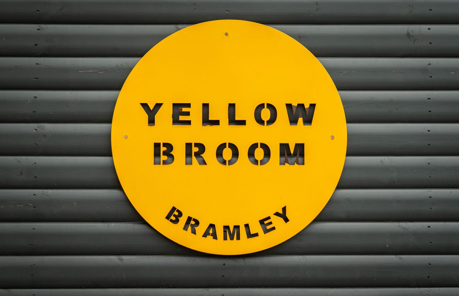 Yellow branded signage mounted on gray corrugated metal panels.