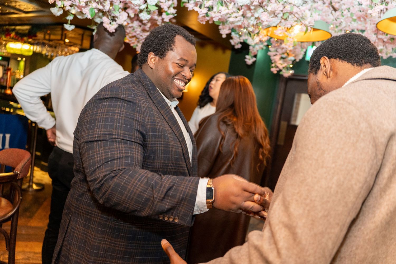 Indoor celebration with cherry blossom decorations and warm lighting overhead.