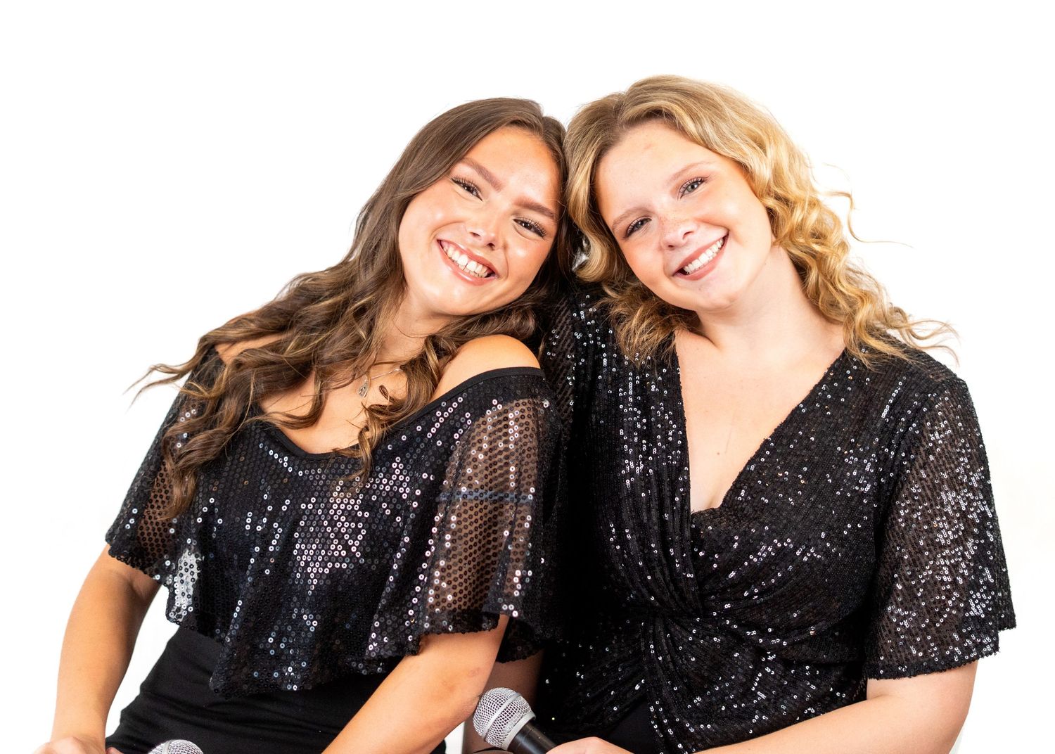 Two performers in glittering black attire pose playfully against a white backdrop.