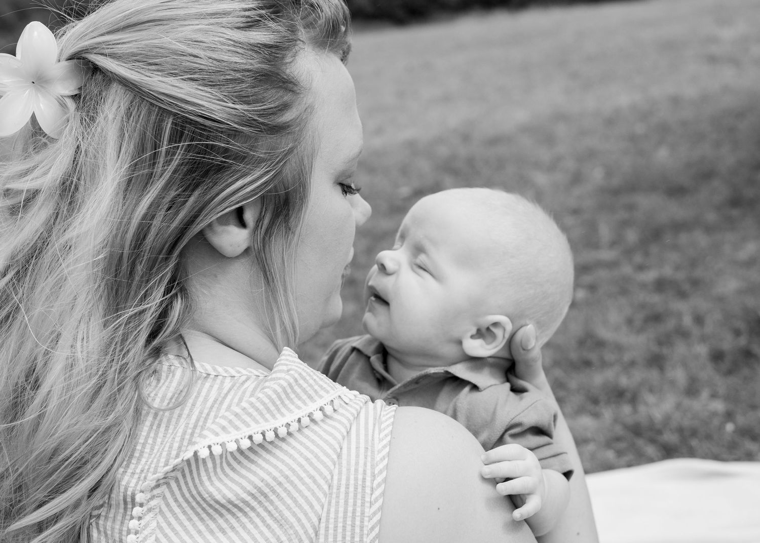 Tender moment between parent and baby in black and white portrait.