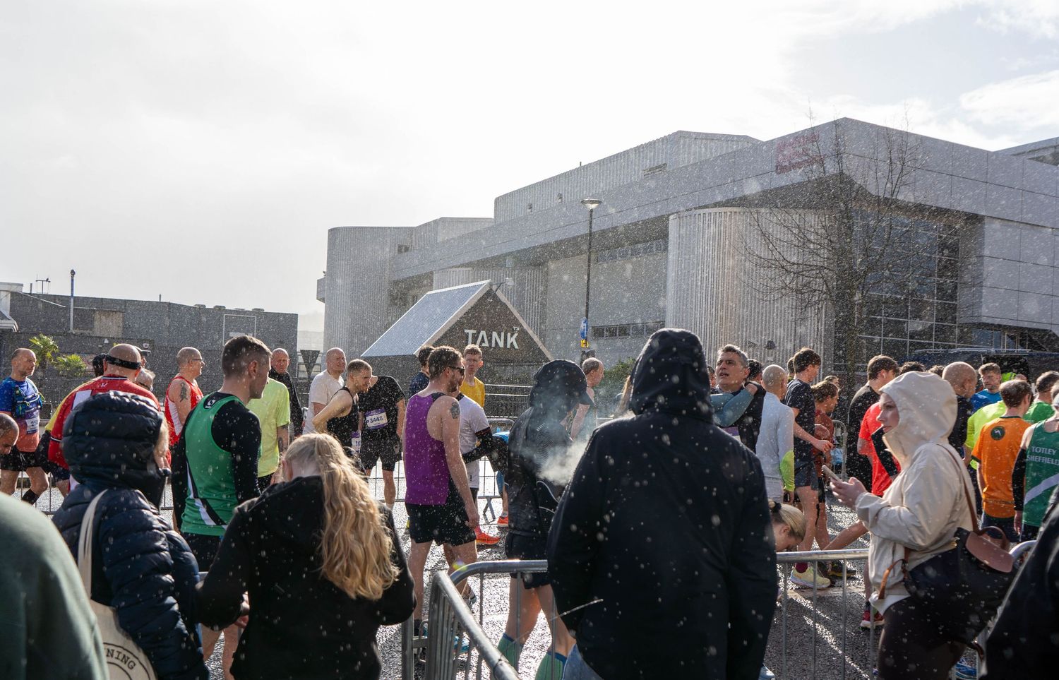 Crowd of runners and spectators gather in urban setting during race event.