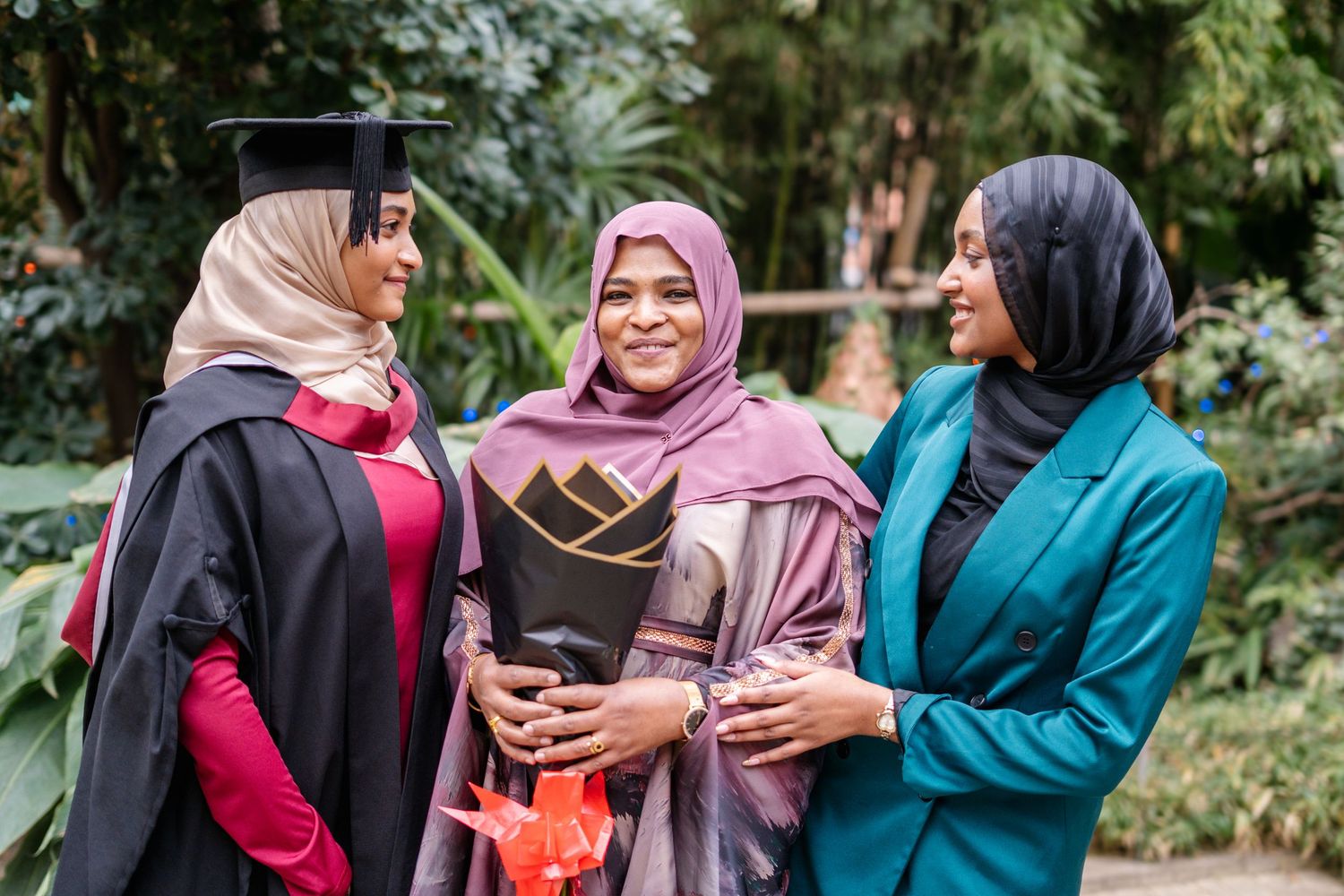A group of graduates in colorful attire celebrating together in a garden.